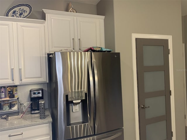 2048 Bristol Grande Way, Orlando, FL 32820 - kitchen with stainless steel fridge with ice dispenser, white cabinets, and light stone countertops