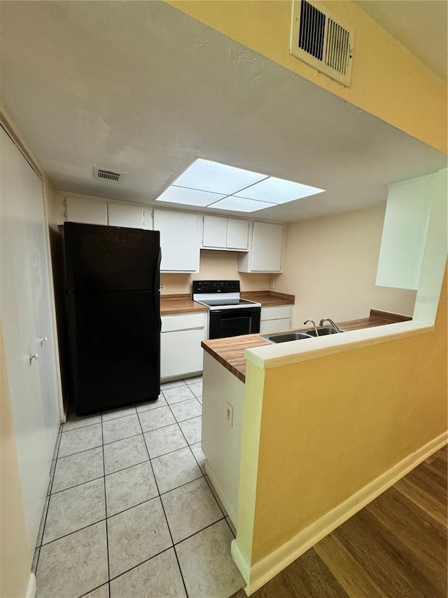 4224 SW 70th Ter Unit A, Gainesville, FL 32608 - kitchen with range with electric stovetop, freestanding refrigerator, white cabinetry, a peninsula, and light tile patterned floors
