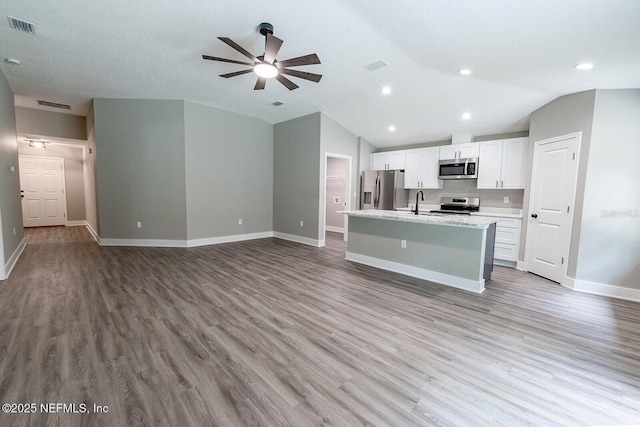 1262 Coral Farms Rd, Florahome, FL 32140 - kitchen featuring appliances with stainless steel finishes, a ceiling fan, vaulted ceiling, an island with sink, and white cabinetry