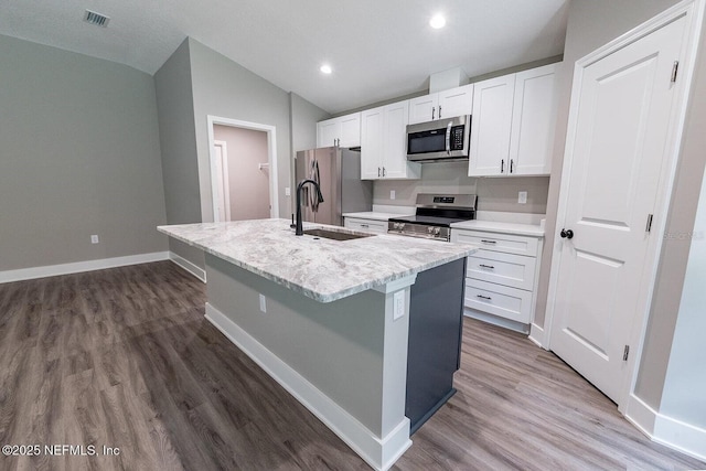 1262 Coral Farms Rd, Florahome, FL 32140 - kitchen featuring stainless steel appliances, lofted ceiling, a kitchen island with sink, white cabinets, and wood finished floors