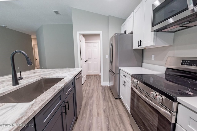 1262 Coral Farms Rd, Florahome, FL 32140 - kitchen featuring stainless steel appliances, light wood-type flooring, white cabinetry, and light stone counters
