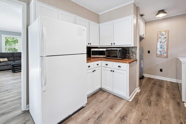 145 SE 904th Ave, Suwannee, FL 32692 - kitchen with freestanding refrigerator, stainless steel microwave, crown molding, wood counters, and light wood-style floors