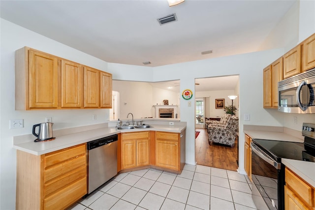 1602 NW 117th Ter, Gainesville, FL 32606 - kitchen with appliances with stainless steel finishes, light countertops, light tile patterned flooring, light brown cabinets, and a peninsula
