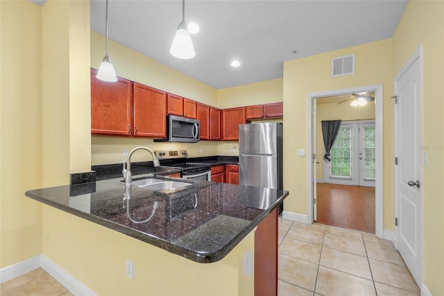 2960 SW 35th Pl Unit 66, Gainesville, FL 32608 - kitchen with appliances with stainless steel finishes, a peninsula, dark stone countertops, light tile patterned floors, and pendant lighting