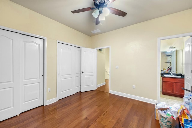 2960 SW 35th Pl Unit 66, Gainesville, FL 32608 - unfurnished bedroom featuring two closets, light wood finished floors, ensuite bath, and a ceiling fan