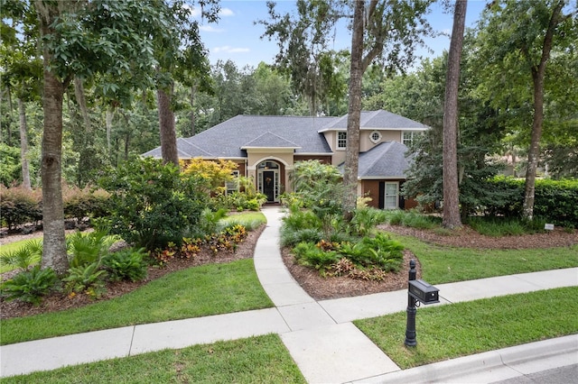5025 NW 51st Pl, Gainesville, FL 32606 - view of front of property with a front lawn, roof with shingles, stucco siding, and view of scattered trees