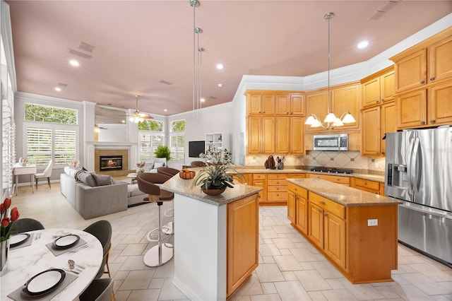 5025 NW 51st Pl, Gainesville, FL 32606 - kitchen featuring stainless steel appliances, a center island, healthy amount of natural light, a ceiling fan, and crown molding