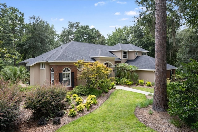 5025 NW 51st Pl, Gainesville, FL 32606 - view of front of house featuring stucco siding, a front lawn, and a shingled roof