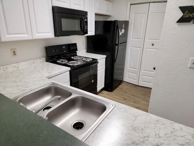 3705 SW 27th St Unit 1112, Gainesville, FL 32608 - kitchen with black appliances, a textured wall, white cabinets, light wood-style floors, and light countertops