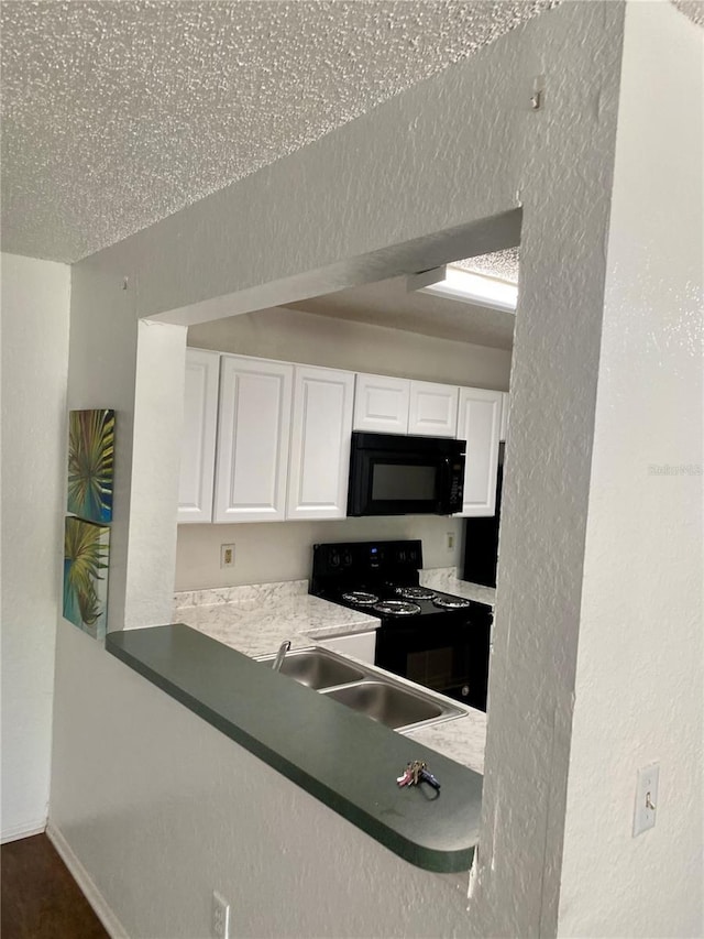 3705 SW 27th St Unit 1112, Gainesville, FL 32608 - kitchen with black appliances, white cabinetry, and a textured wall