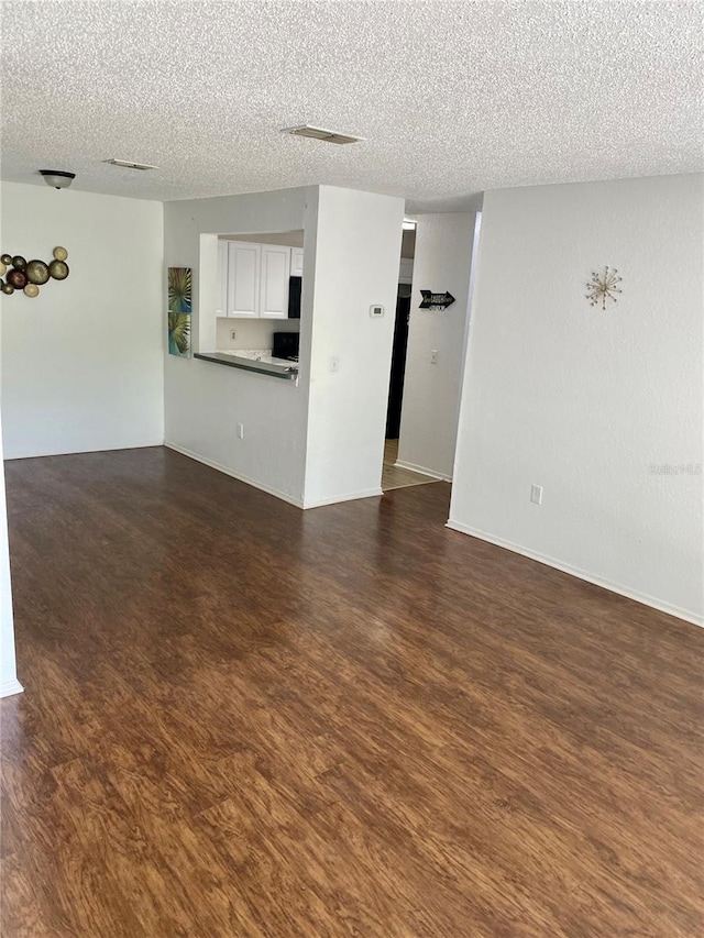 3705 SW 27th St Unit 1112, Gainesville, FL 32608 - unfurnished living room featuring a textured ceiling and dark wood-style floors