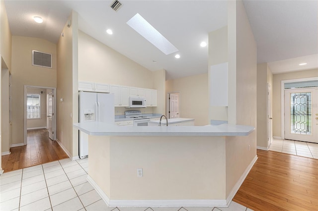 8036 SW 72nd Pl, Gainesville, FL 32608 - kitchen featuring white appliances, high vaulted ceiling, a skylight, light countertops, and a peninsula