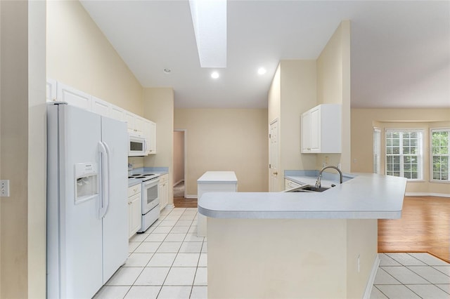 8036 SW 72nd Pl, Gainesville, FL 32608 - kitchen featuring white appliances, light tile patterned floors, light countertops, a peninsula, and a skylight