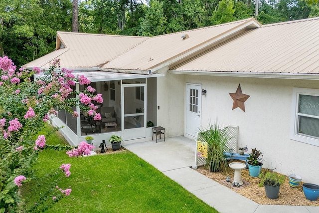 8488 NW 39th Ter, Gainesville, FL 32653 - rear view of house with a sunroom, stucco siding, a metal roof, and a yard