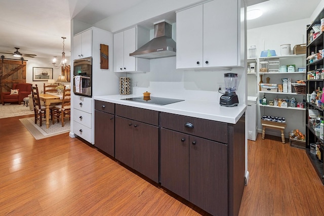 8488 NW 39th Ter, Gainesville, FL 32653 - kitchen with wall chimney exhaust hood, black electric cooktop, white cabinets, light wood finished floors, and ceiling fan
