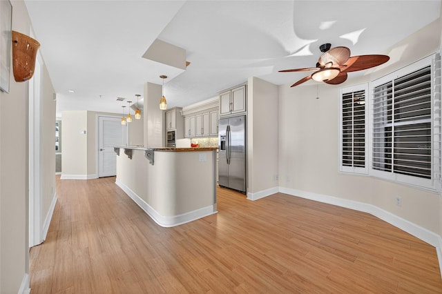 4555 S Atlantic Ave Unit 4603, Ponce Inlet, FL 32127 - kitchen with stainless steel refrigerator with ice dispenser, a kitchen breakfast bar, a ceiling fan, cream cabinets, and light wood-type flooring