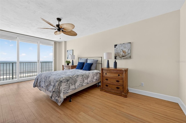 4555 S Atlantic Ave Unit 4603, Ponce Inlet, FL 32127 - bedroom with access to exterior, a water view, light wood-style floors, expansive windows, and ceiling fan