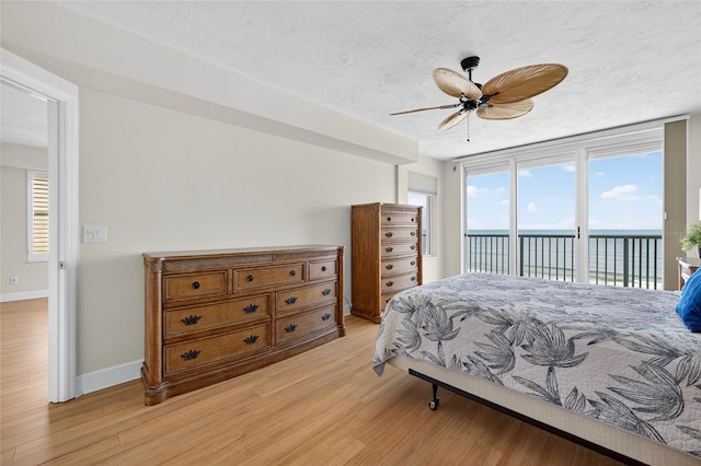 4555 S Atlantic Ave Unit 4603, Ponce Inlet, FL 32127 - bedroom featuring access to outside, light wood-style floors, a water view, a textured ceiling, and a ceiling fan