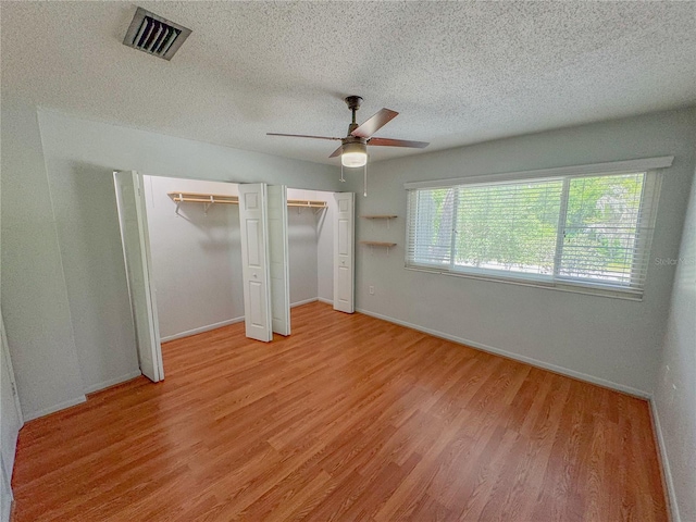 2710 SW 14th Dr, Gainesville, FL 32608 - unfurnished bedroom featuring multiple closets, light wood-style flooring, a textured ceiling, and ceiling fan