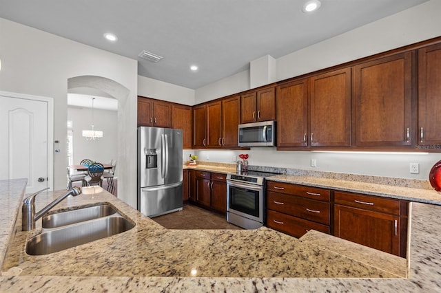 2750 NW 143rd Way, Newberry, FL 32669 - kitchen with appliances with stainless steel finishes, light stone countertops, a chandelier, recessed lighting, and arched walkways