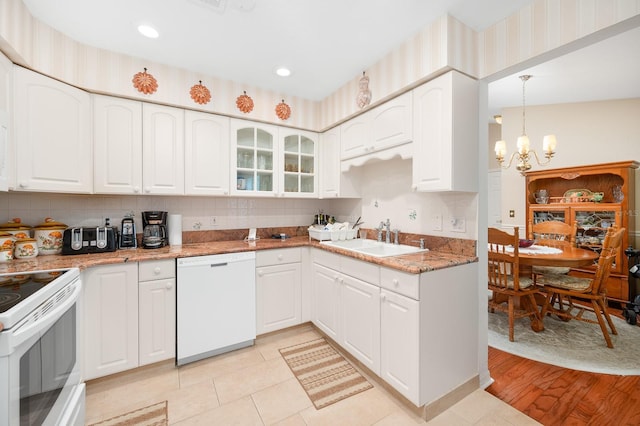 4705 SW 80th Ter, Gainesville, FL 32608 - kitchen with white appliances, a chandelier, white cabinets, backsplash, and glass insert cabinets