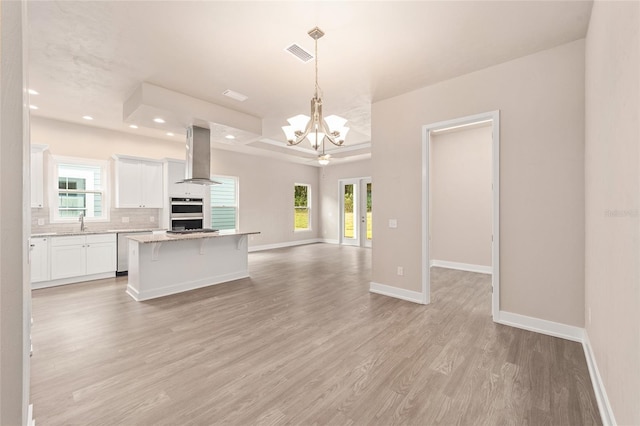 1080 NW 132nd Blvd, Newberry, FL 32669 - kitchen with exhaust hood, open floor plan, light wood-style flooring, a tray ceiling, and white cabinetry