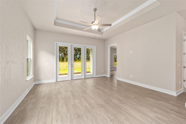 1080 NW 132nd Blvd, Newberry, FL 32669 - empty room featuring a tray ceiling, healthy amount of natural light, a ceiling fan, and light wood-style flooring