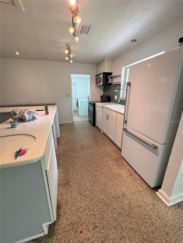 1215 NE 21st Ave, Gainesville, FL 32609 - kitchen featuring freestanding refrigerator, range with electric cooktop, stainless steel microwave, backsplash, and white cabinetry