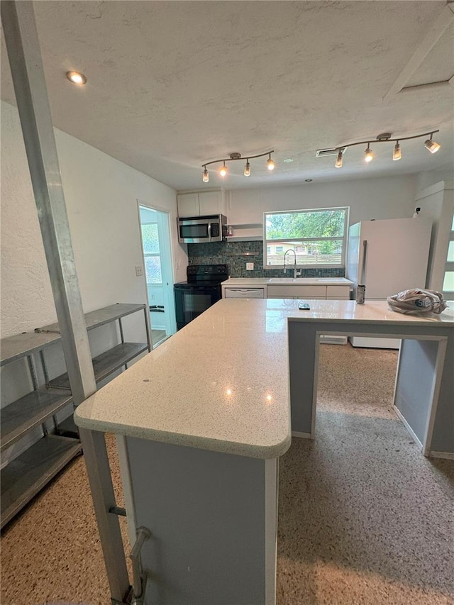 1215 NE 21st Ave, Gainesville, FL 32609 - kitchen with black range with electric stovetop, stainless steel microwave, healthy amount of natural light, and white cabinetry