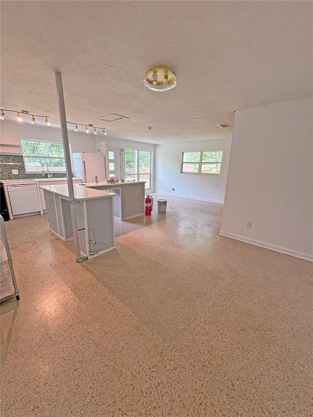 1215 NE 21st Ave, Gainesville, FL 32609 - kitchen with open floor plan, white refrigerator, a kitchen island, white cabinets, and a textured ceiling