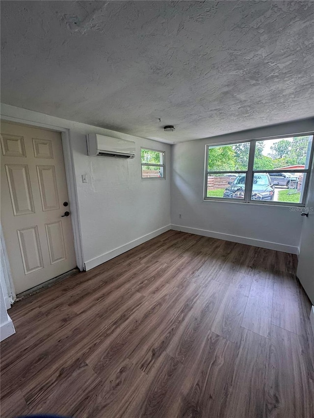 1215 NE 21st Ave, Gainesville, FL 32609 - unfurnished room featuring a wall mounted air conditioner, dark wood-type flooring, and a textured ceiling