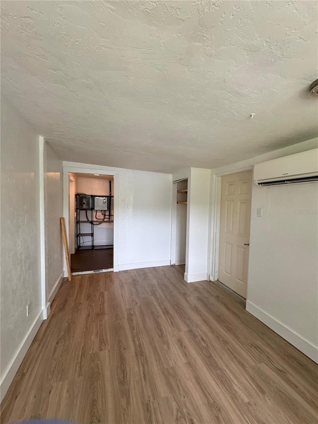 1215 NE 21st Ave, Gainesville, FL 32609 - unfurnished bedroom with wood finished floors, an AC wall unit, a textured ceiling, and a closet