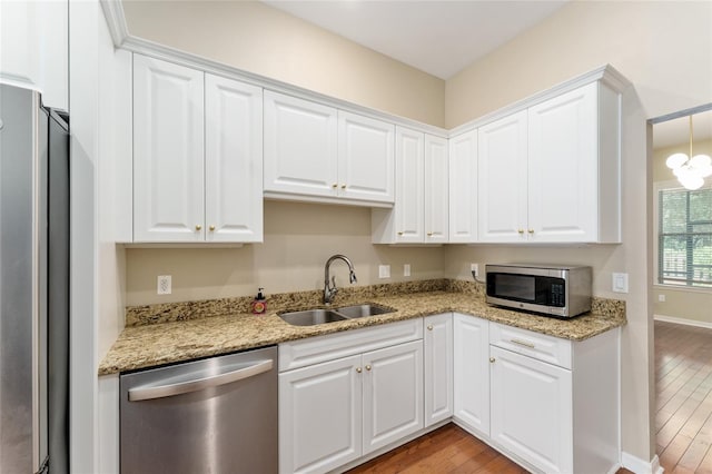8650 SW 26th Ln, Gainesville, FL 32608 - kitchen featuring appliances with stainless steel finishes, light wood-style floors, white cabinetry, and light stone counters