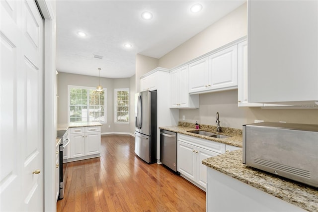 8650 SW 26th Ln, Gainesville, FL 32608 - kitchen featuring appliances with stainless steel finishes, white cabinets, light wood finished floors, recessed lighting, and light stone counters