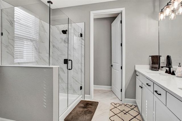 full bath featuring marble finish floor, a sink, a marble finish shower, double vanity, and baseboards