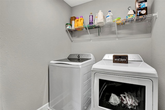 clothes washing area with independent washer and dryer, laundry area, and baseboards