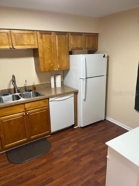 kitchen with white appliances, sink, and dark hardwood / wood-style flooring