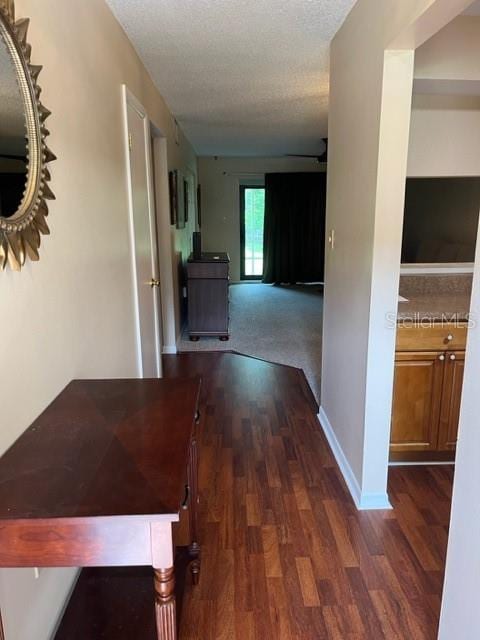 hallway with dark hardwood / wood-style flooring and a textured ceiling