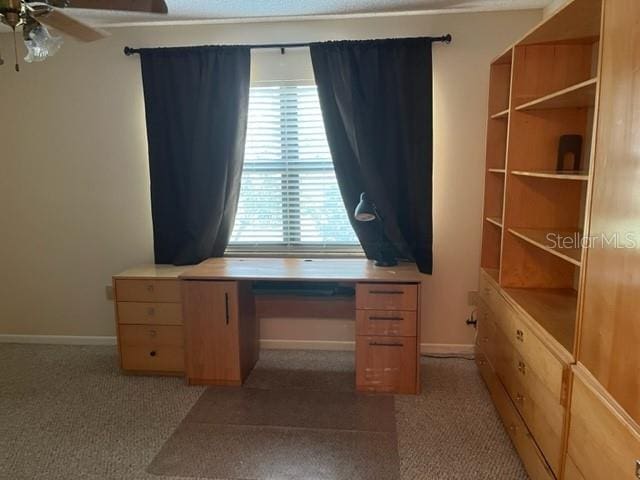 unfurnished office featuring ceiling fan and dark colored carpet