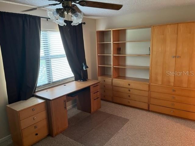 unfurnished office featuring light carpet, a textured ceiling, and ceiling fan