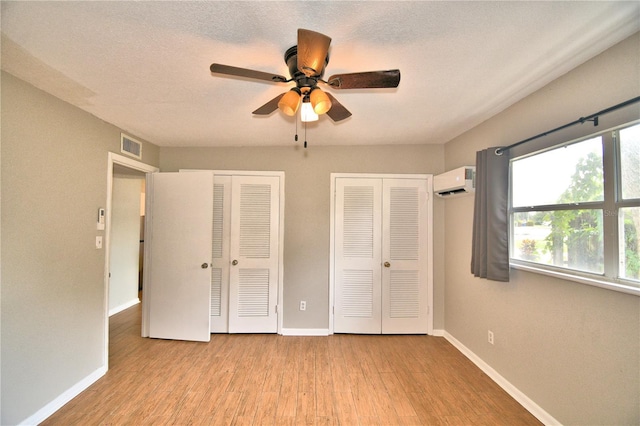 unfurnished bedroom with baseboards, multiple closets, and wood finished floors