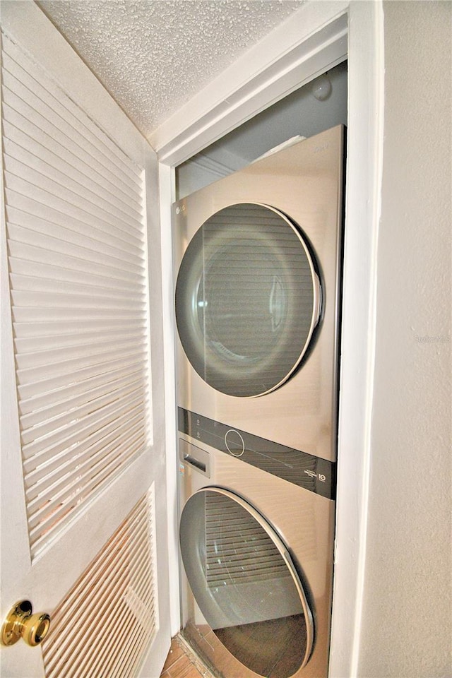 laundry room with stacked washer / dryer, laundry area, and a textured ceiling