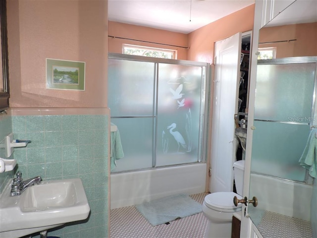 full bathroom featuring toilet, sink, tile patterned floors, and enclosed tub / shower combo