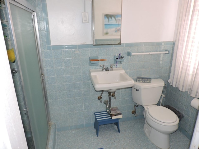 bathroom with a shower with shower door, toilet, and tile walls