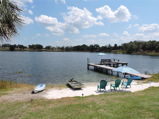 view of dock with a water view and a yard