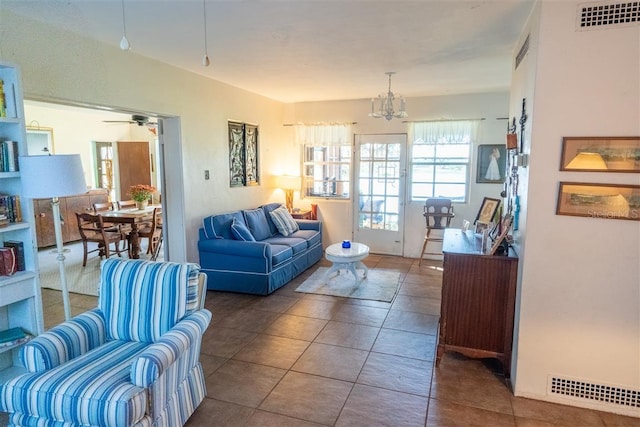 tiled living room featuring ceiling fan with notable chandelier