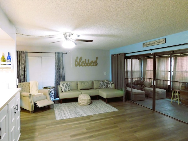 living room with light hardwood / wood-style floors, ceiling fan, and a textured ceiling