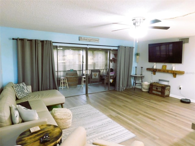 living room featuring ceiling fan, light hardwood / wood-style flooring, and a textured ceiling