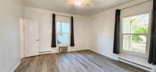 unfurnished room with a baseboard radiator, a wall unit AC, and light hardwood / wood-style flooring