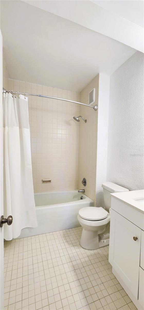 full bathroom with shower / tub combo with curtain, vanity, toilet, and tile patterned flooring